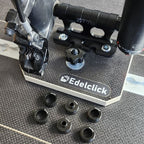 Présentation de notre produit "support axe vélo", fixé sur un rail aéro. Un vélo est monté sur ce support par sa fourche avant et différentes calles d'adaptation selon le type de fourche sont disposées à proximité.